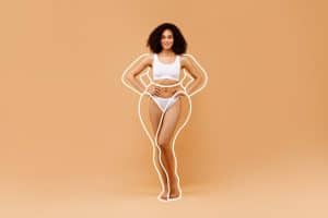 Slim woman with white lines drawn outside her body to represent weight loss followed by body contouring surgery